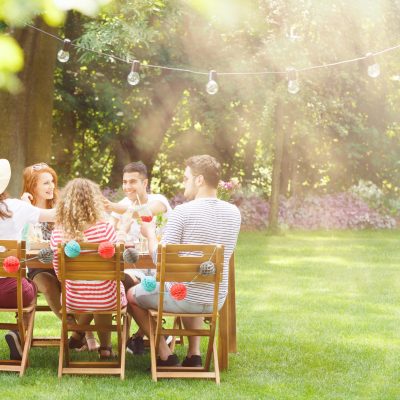 Group of smiling friends eating lunch at  a garden party